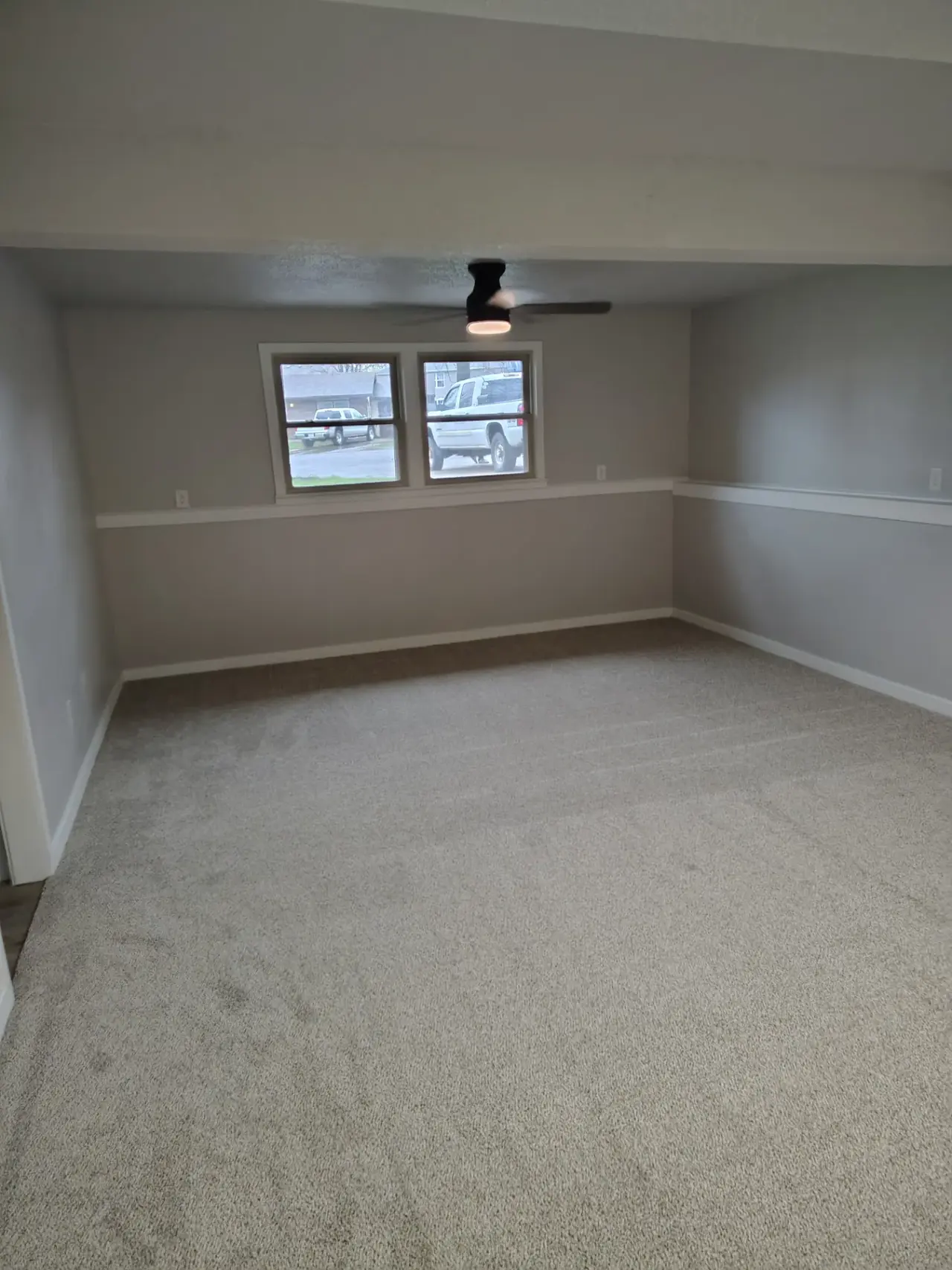 Finished basement with carpet, windows, and ceiling fan
