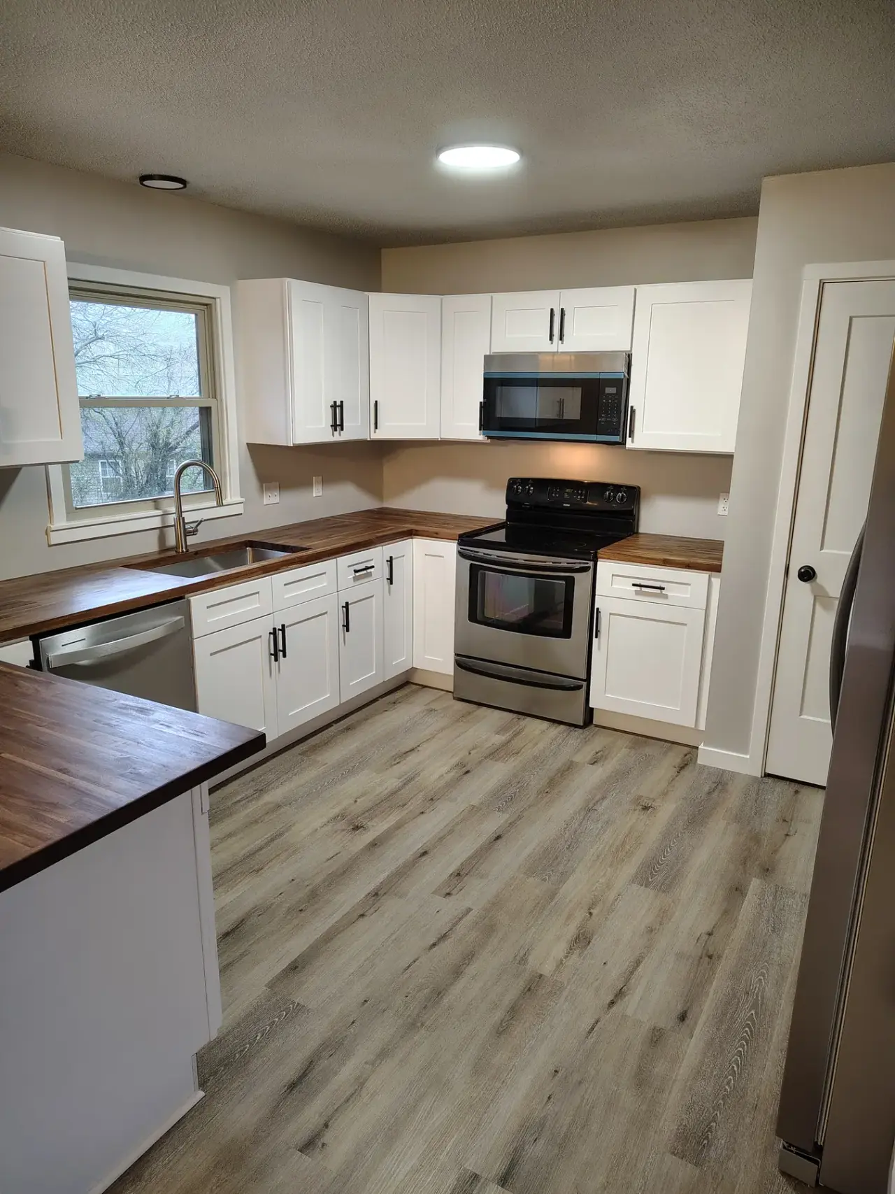 Renovated kitchen with white cabinets and wood countertops