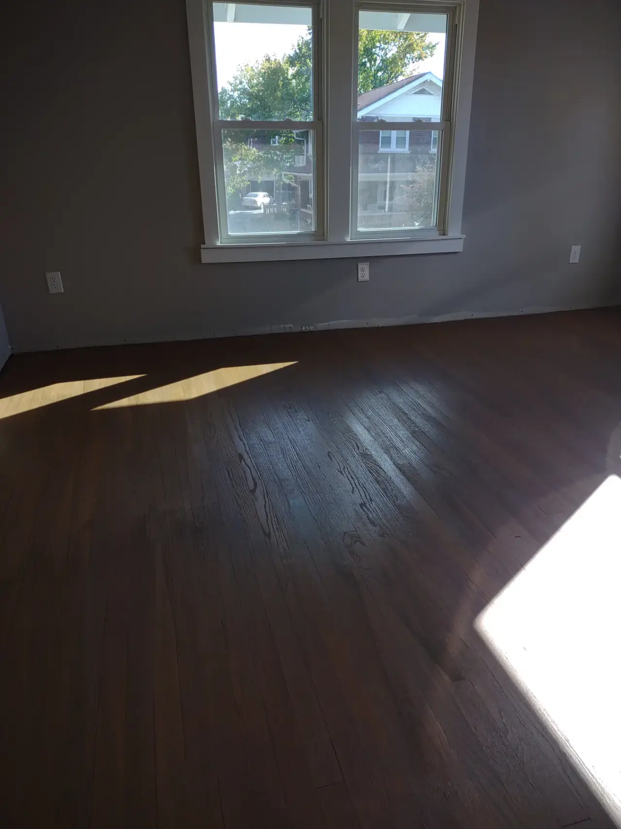 Refinished hardwood floor in a room with large windows